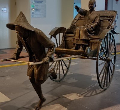 Statue of a man pulling a ricksaw.