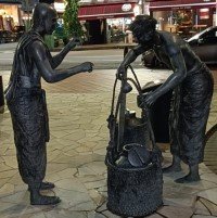 Statues of a man buying food from a food seller.
