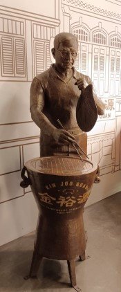 Statue of a man barbecuing bakkwa (barbecued meat using coal) inside Kim Joo Guan at 257 South Bridge Rd.